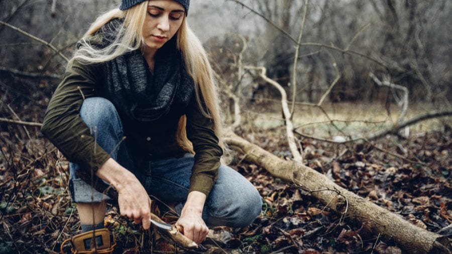 hiker cutting wood with knife