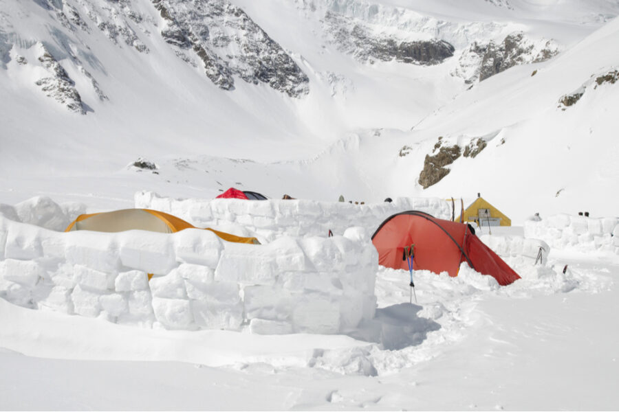 tents inside a windbreak snow wall protecting them from strong winds