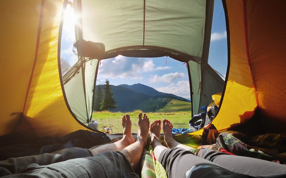 Two,People,Lying,In,Tent,With,A,View,Of,Mountains.